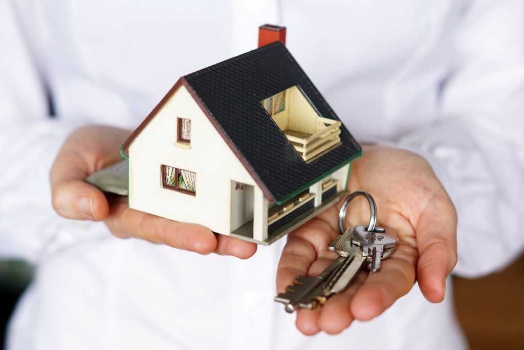 person-holding-keys-model-house